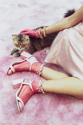 Woman wearing pink petting cat.